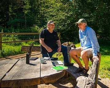 zwei Männer sitzen im Wald auf einer Bank